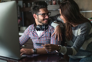 young couple smiling with the computer
